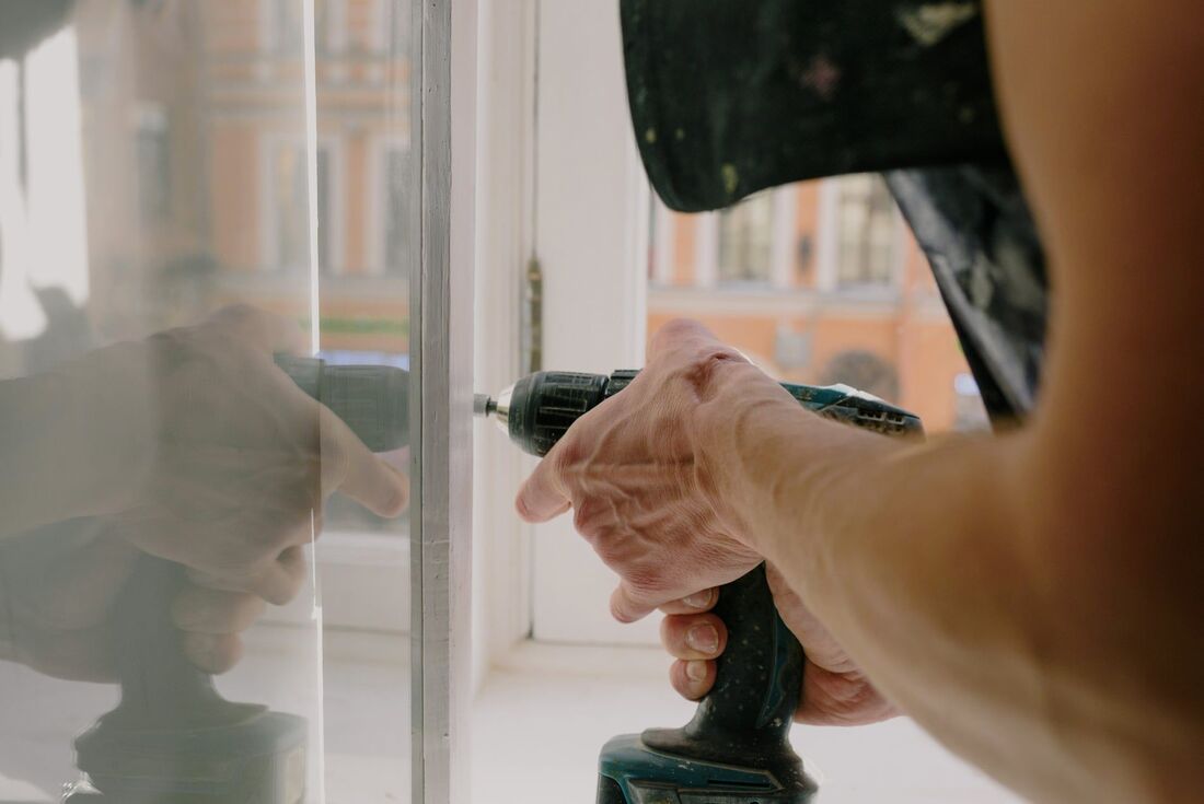 Carpintero colocando una bisagra en una ventana. Foto tomada en Vigo, Pontevedra.